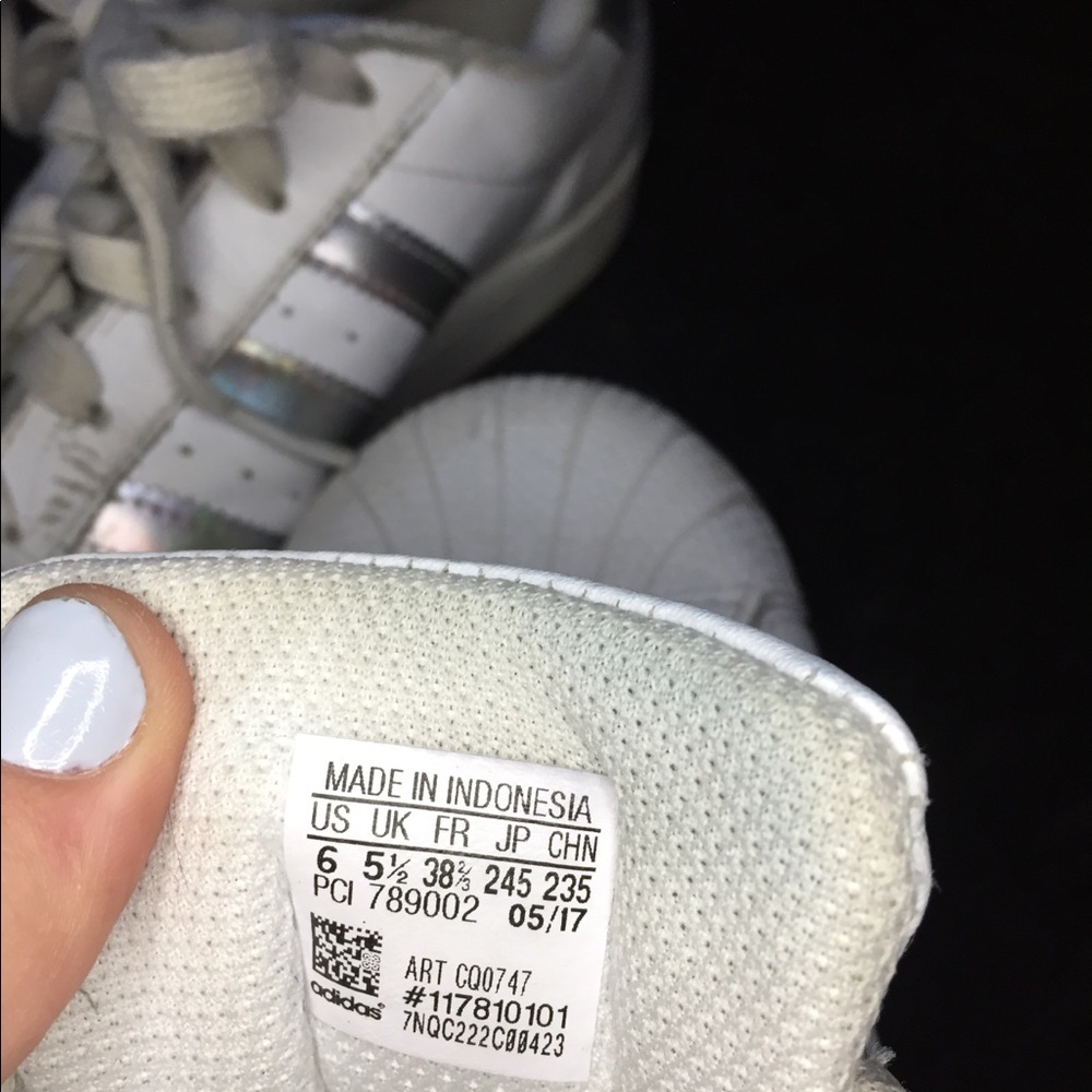 White Adidas super stars with holographic stripes.